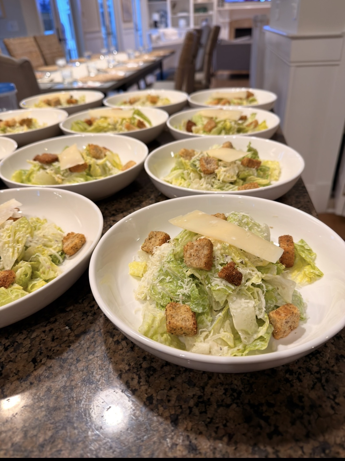Caesar salads with shaved parmesan and croutons plated for service