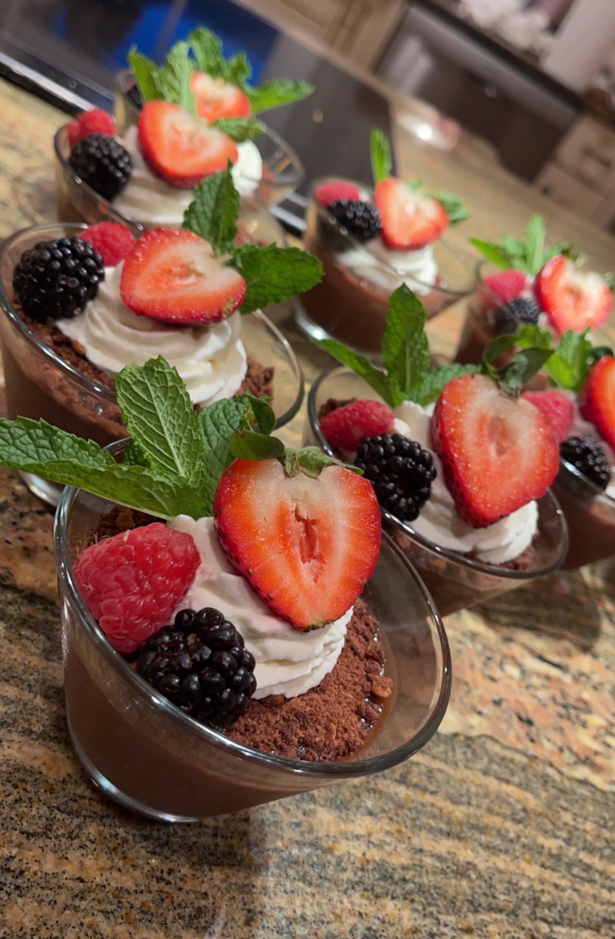 Chocolate mousse cups topped with whipped cream, berries, and mint
